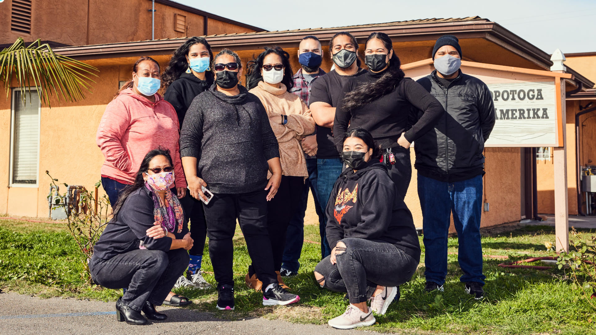 group of NHPI community members wearing masks standing in front of a community center