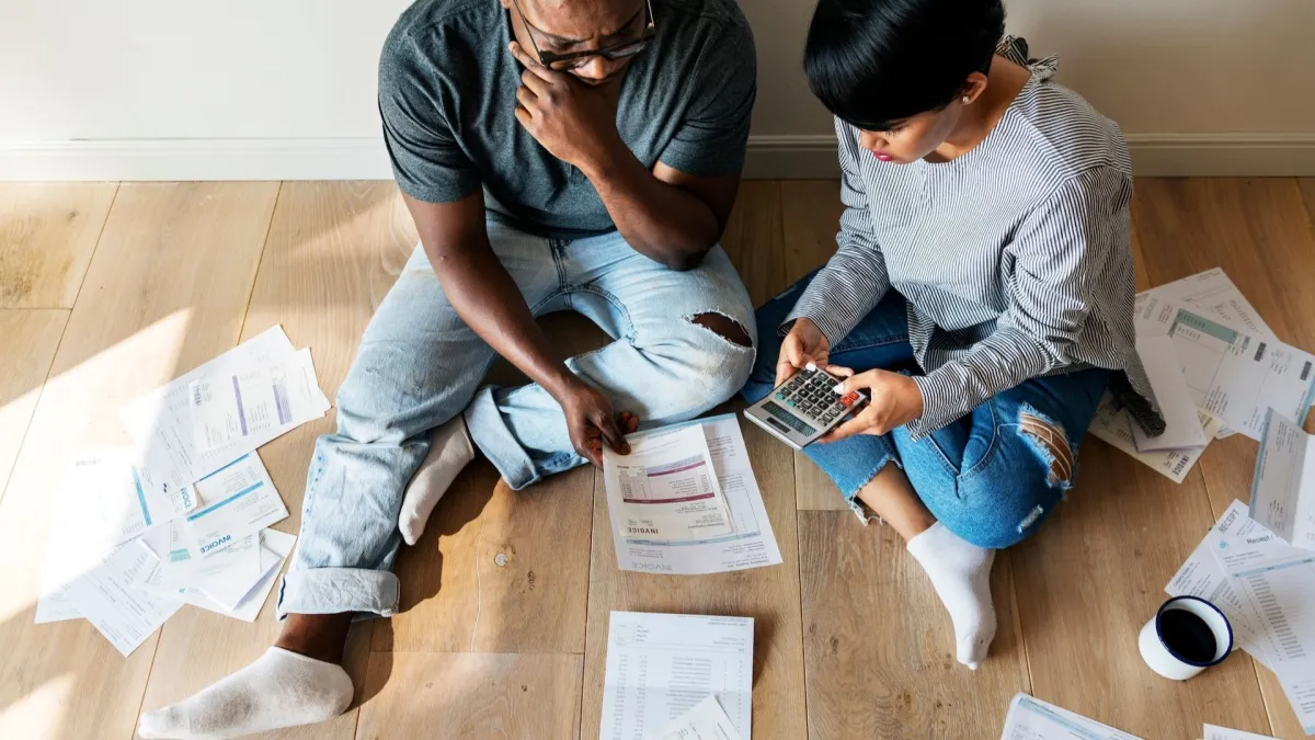 Photo: Couple with calculator sitting on floor looking at bills