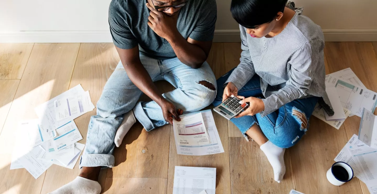 Photo: Couple with calculator sitting on floor looking at bills