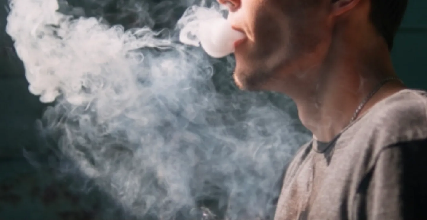 Photo of man exhaling e-cigarette vapor
