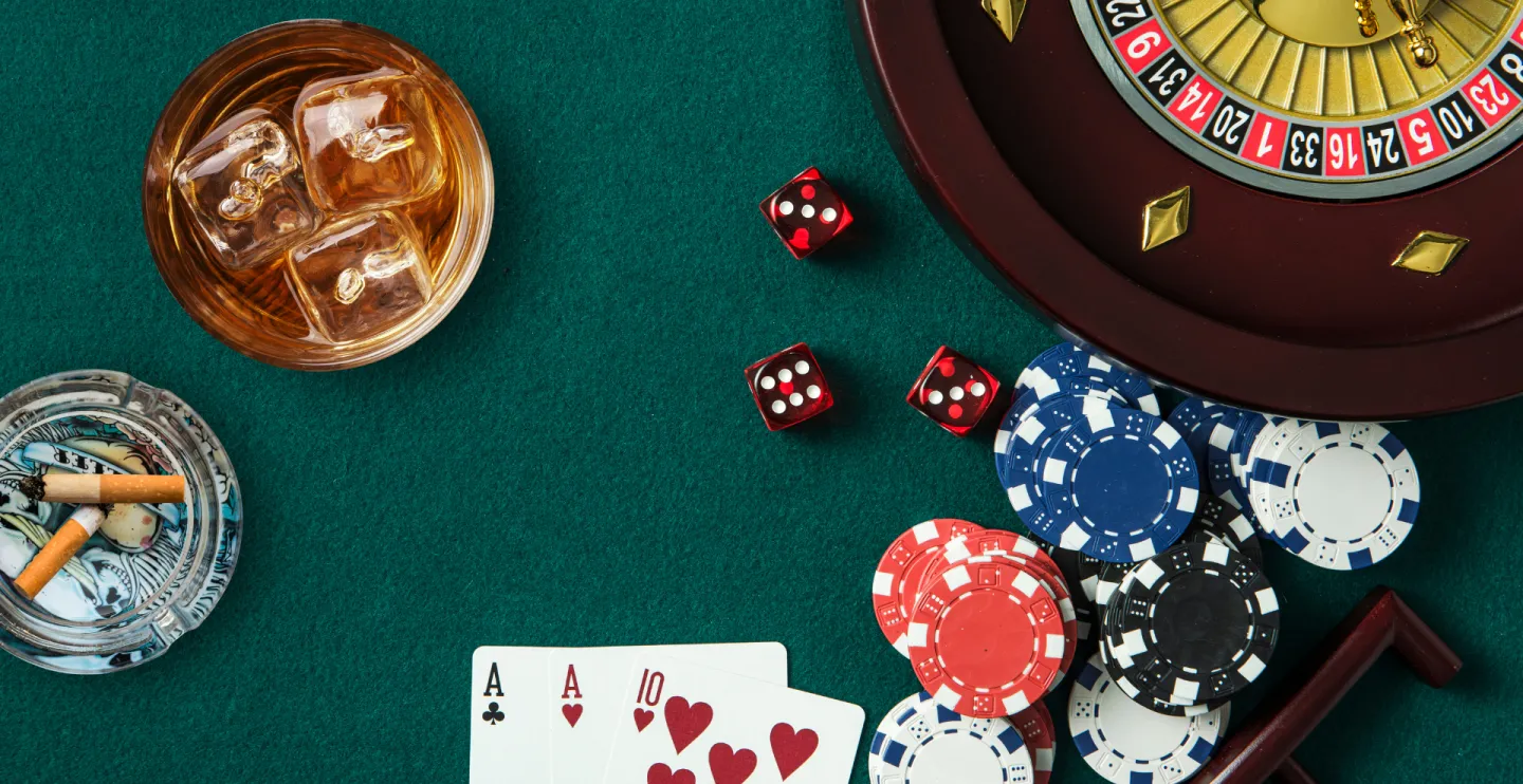 Overhead shot of playing cards, dice, casino chips and a roulette wheel