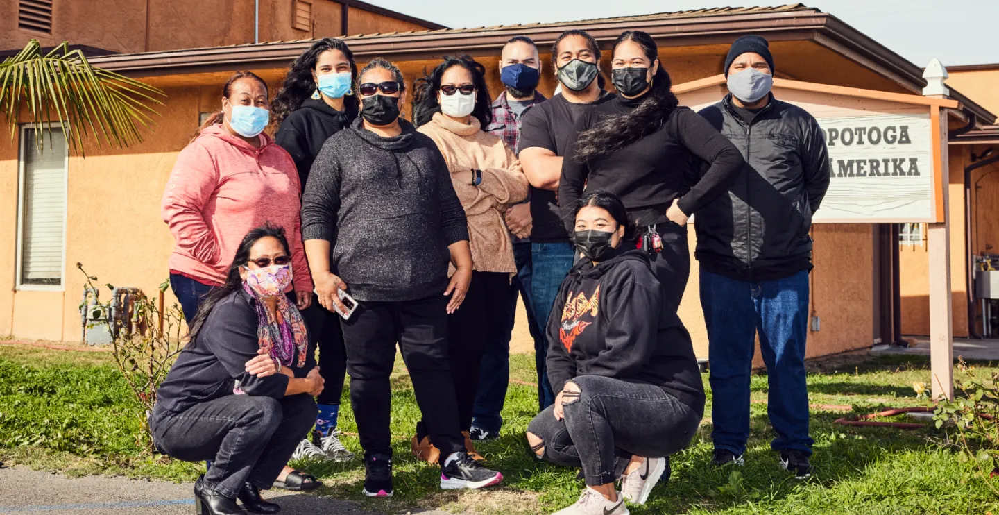group of NHPI community members wearing masks standing in front of a community center