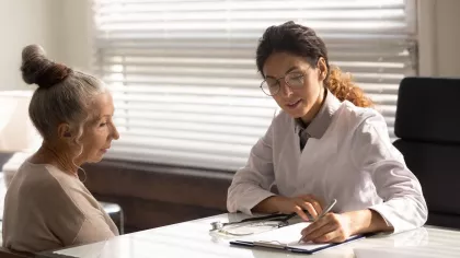 Doc at work. Focused doctor in glasses write diagnosis symptoms of mature woman patient in medical case. Female family therapist interview sick elderly lady take notes fill in paper declaration form