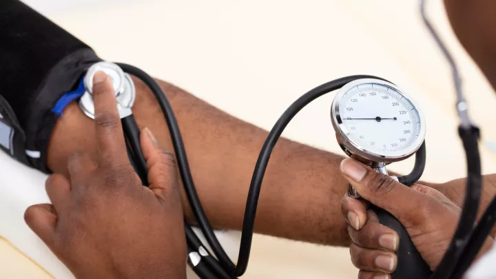 Close-up Of Doctor's Hand Measuring Blood Pressure Of Male Patient