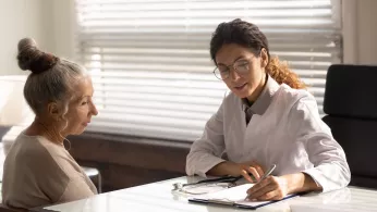 Doc at work. Focused doctor in glasses write diagnosis symptoms of mature woman patient in medical case. Female family therapist interview sick elderly lady take notes fill in paper declaration form