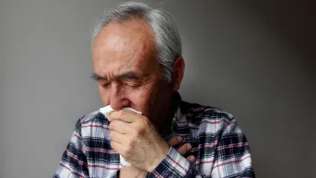 older man coughing into a napkin