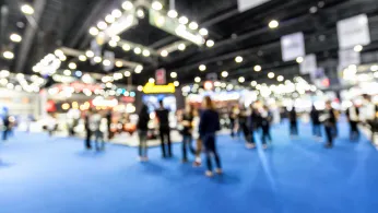 blurry photo of a conference exhibit hall with people standing around