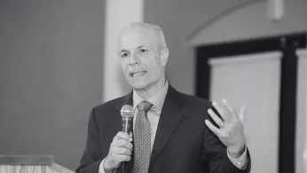 black and white photo of rick brown speaking into a microphone